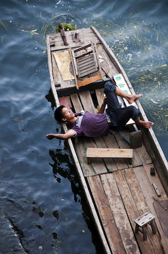 Oriantal man sleeping accross fishing boat